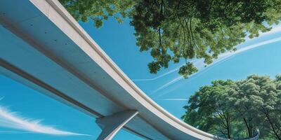 Low angle view of a highway bridge with trees in the background under clear blue sky. photo