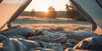 A bed in a tent with the sun setting behind it photo