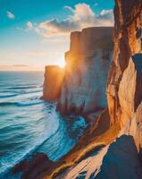 The sun setting over a cliff with waves and rocks photo
