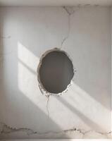 A distressed white wall featuring an unusual hole that adds character and intrigue to the setting. photo