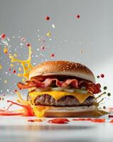 A hamburger with bacon, cheese and sauce splashing on it photo