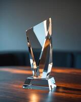 Crystal award trophy displayed on a wooden table with soft lighting and a blurred background. photo