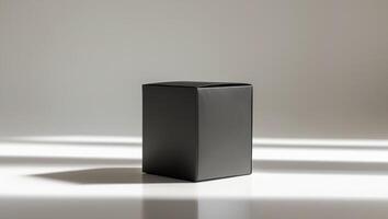 Premium black matte packaging box on reflective surface with subtle shadows for branding showcase photo