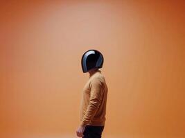 Man in a black helmet stands in front of a bright orange background. photo