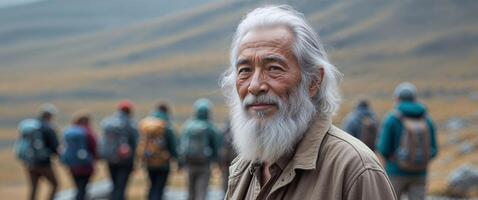 Senior man with a white beard on the background of a group of hikers. photo