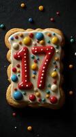 Festive cookie decorated with colorful icing and sprinkles for a 17th birthday celebration in a dark setting photo