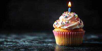 Brightly lit cupcake with colorful frosting and a candle stands out against a dark background for a festive celebration photo