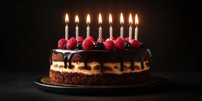Delicious chocolate cake with raspberry topping and candles lit for celebration at a festive gathering photo