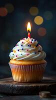 Colorful cupcake with a lit candle celebrating a birthday or special occasion at night photo
