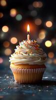Colorful cupcake with candle and festive bokeh background celebrating a birthday at nighttime photo