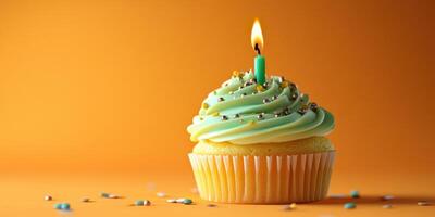 Celebrating with a cupcake adorned with a candle on a vibrant orange background for a festive occasion photo