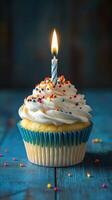 Colorful cupcake with a single candle burning on top, ready for celebration in a cozy setting photo
