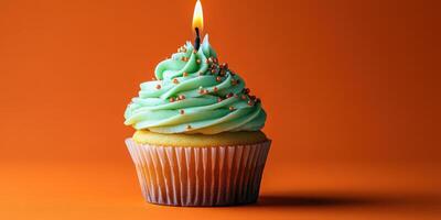 Colorful cupcake with mint frosting and a candle on a vibrant orange background during a celebration photo