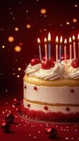 Colorful birthday cake with lit candles and festive decorations on a red background photo