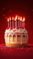 Brightly decorated birthday cake with candles glowing against a red background photo