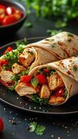 Delicious chicken wraps filled with fresh vegetables on a black plate with herbs and spices in the background photo