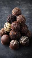 Delicious assortment of handcrafted chocolate truffles arranged in a beautiful pyramid on a dark surface photo
