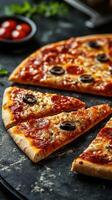 Slices of pepperoni pizza with black olives on a dark stone surface photo