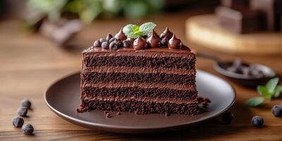 Decadent chocolate cake slice on a rustic wooden table with chocolate chips and mint garnish photo