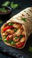 Delicious chicken wrap filled with fresh vegetables and herbs on a dark background photo