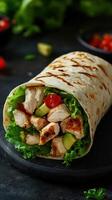 Delicious grilled chicken wrap filled with fresh vegetables and herbs on a dark surface photo