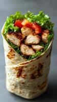 Grilled chicken wrap with fresh lettuce and tomatoes served on a soft tortilla in a casual setting photo