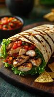 Grilled chicken wrap with fresh salsa served with tortilla chips on a wooden board photo