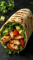 Grilled chicken wrap with fresh vegetables and avocado in a tortilla on a dark background photo