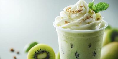 Refreshing kiwi smoothie topped with whipped cream and mint leaves served in a clear cup photo