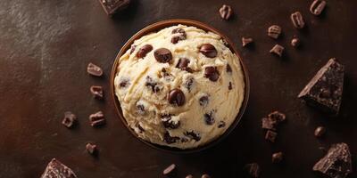 Delightful bowl of chocolate chip ice cream surrounded by chocolate pieces captured in a cozy setting photo