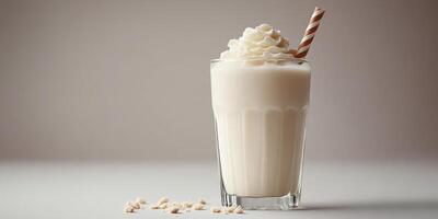 Creamy milkshake served in a glass with whipped topping and a straw on a plain background photo