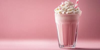 Creamy pink milkshake in a tall glass with whipped cream and a straw on a light pink background photo