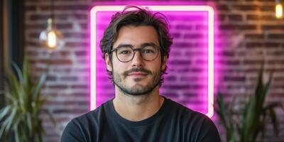 Young man with glasses poses confidently in a modern cafe with neon lights photo