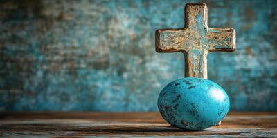 Rustic wooden cross beside a vibrant blue Easter egg on a textured background photo