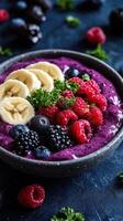 Colorful smoothie bowl topped with fresh fruit and garnished with mint on a dark surface in a cozy kitchen setting photo