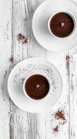 Delicious chocolate desserts served in white bowls on rustic wooden table photo