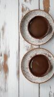 Two cups of rich hot chocolate served on rustic plates displayed on a wooden table in a cozy setting photo