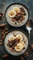 Healthy chia seed pudding topped with banana slices and granola, served in two black bowls photo