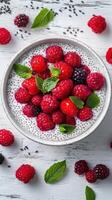Fresh berries and mint served atop a creamy chia seed pudding in a rustic bowl photo