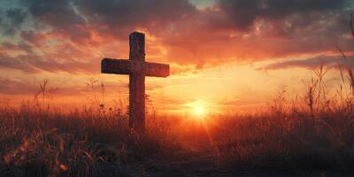 Cross silhouette against a breathtaking sunset in a quiet field with colorful clouds and tall grass photo