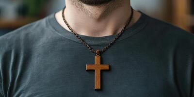 Wooden cross pendant hangs from chain on a man's neck indoors during a calm moment of reflection photo