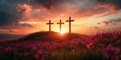 Three crosses stand on a hill surrounded by vibrant flowers as the sun sets behind them photo
