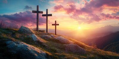 Three crosses on a hillside bathed in golden sunset light with dramatic clouds and distant mountains photo
