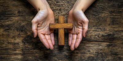 Hands holding a wooden cross on a rustic wooden surface symbolizing faith and spirituality photo