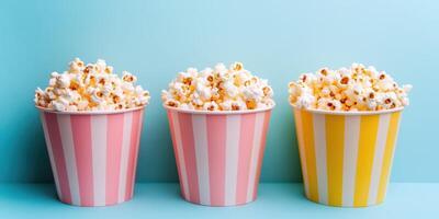 Colorful striped popcorn containers filled with fluffy popcorn against a light blue background in a cheerful setting photo