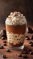 Delicious layered chocolate and coffee dessert topped with whipped cream served in a clear glass photo