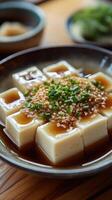 Freshly prepared tofu topped with chives and sesame in a traditional setting photo