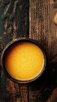Vibrant orange drink served in a rustic bowl on a weathered wooden table in an inviting setting photo