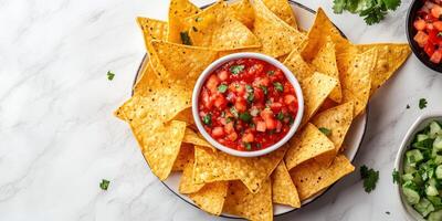 Freshly made tortilla chips served with salsa and garnished with cilantro on a marble countertop photo