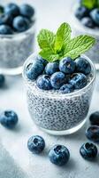 Chia seed pudding topped with fresh blueberries and mint leaves served in clear glass cups on a light background photo